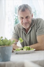 Older Caucasian man eating salad