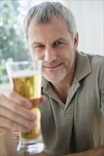 Older Caucasian man toasting with beer glass
