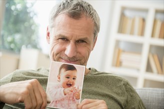 Proud grandfather showing photograph of baby granddaughter
