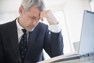 Frustrated older Caucasian businessman using laptop