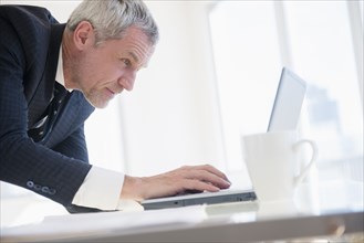 Older Caucasian businessman using laptop