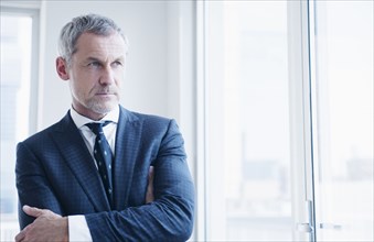 Pensive older Caucasian businessman looking out window