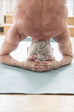 Older Caucasian man doing headstand on exercise mat