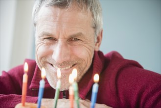 Older Caucasian man smiling at birthday cake