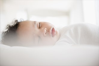 Mixed Race baby boy sleeping on bed