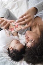 Mother posing for cell phone selfie with sleeping baby son