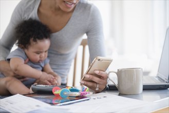Mother holding baby son in lap texting on cell phone