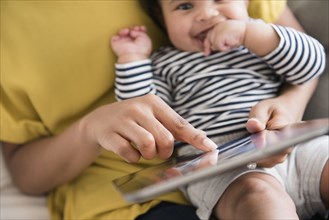 Mother holding baby son using digital tablet