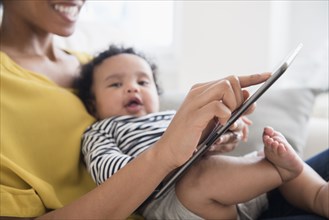 Mother holding baby son using digital tablet