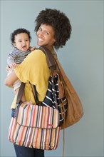 Mother carrying three bags and baby son