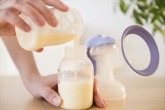Caucasian woman pouring breast milk into bottle