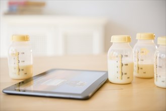 Digital tablet near bottles of breast milk