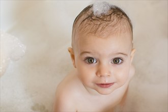 Caucasian baby girl in bathtub with soap in hair