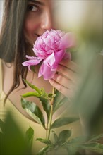 Hispanic woman smelling pink flower