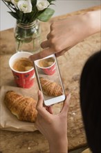 Hispanic woman photographing breakfast with cell phone