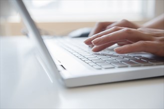 Hands of Hispanic woman typing on laptop