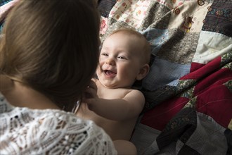 Caucasian mother playing with baby son on blanket