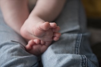 Feet of Caucasian baby boy on legs of mother