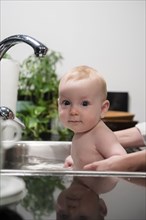 Caucasian boy bathing in sink