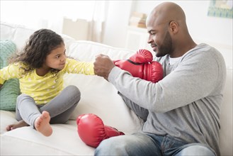 Father helping daughter with boxing gloves
