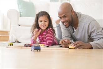 Father and daughter playing with toy cars on floor