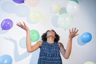 Black woman watching falling balloons