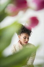 Pensive glamorous Black woman behind flowers