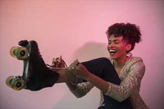 Glamorous Black woman tying roller skate