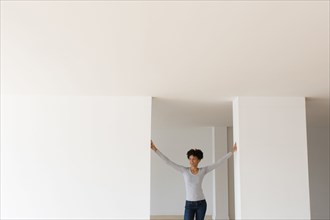 Black woman leaning in doorway in empty apartment