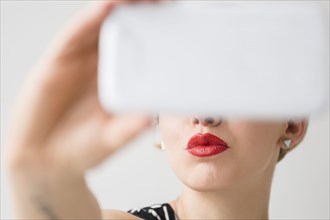 Red lips of woman posing for cell phone selfie