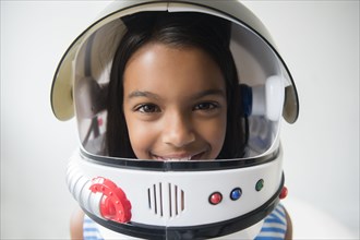 Mixed Race girl wearing astronaut helmet