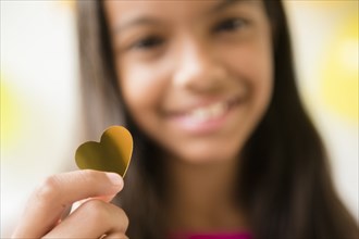 Mixed Race girl holding golden heart-shape confetti
