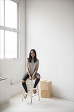 Mixed Race woman sitting on stool in corner