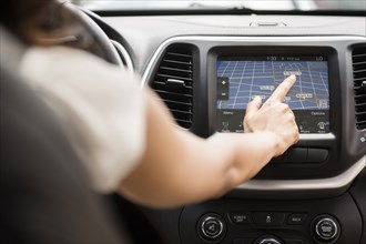 Mixed Race woman using touch screen navigation map in car