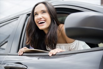 Smiling Mixed Race woman leaning out car window