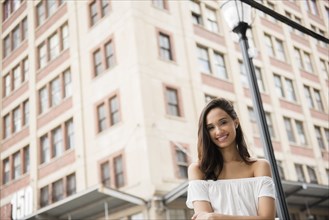 Smiling Mixed Race woman posing in city