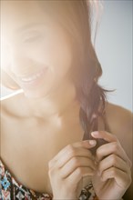 Smiling Mixed Race woman braiding hair