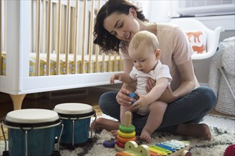 Caucasian mother and baby son playing with toys on floor