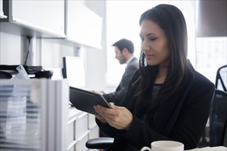 Mixed Race businesswoman using digital tablet in office