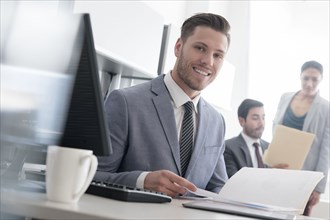 Smiling businessman reading file in office