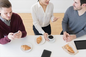 Business people eating croissants at table
