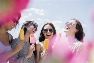 Laughing women eating flavored ice outdoors