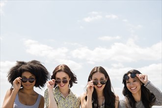 Portrait of smiling women holding sunglasses outdoors