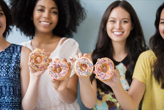 Portrait of smiling women posing with donuts