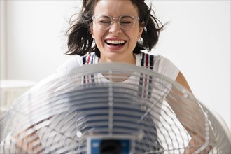 Hispanic woman cooling off using fan