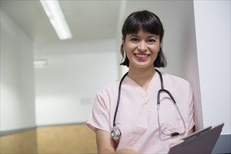 Smiling Hispanic nurse holding clipboard