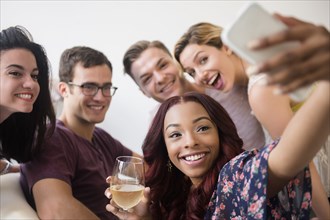 Smiling friends posing for cell phone selfie