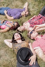 Smiling friends relaxing in sunny grass field