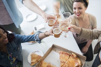 Friends toasting over box of pizza