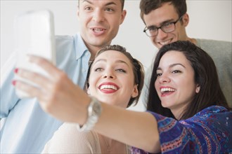 Smiling Caucasian friends posing for cell phone selfie